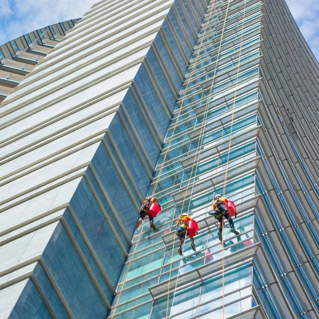 group of specialists cleaning the glass facade of a skyscraper,